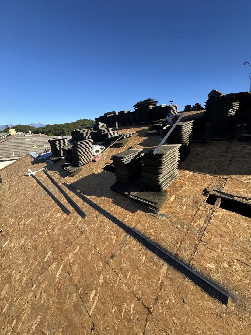 Concrete tile stacked in courses on fresh plywood decking, ready to be relaid.
