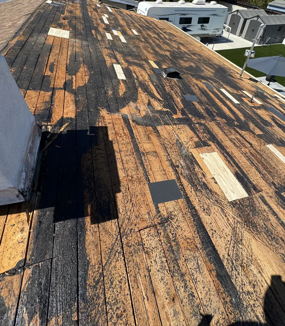 Roof stripped to the original board deck with worn boards patched before the new system goes on.